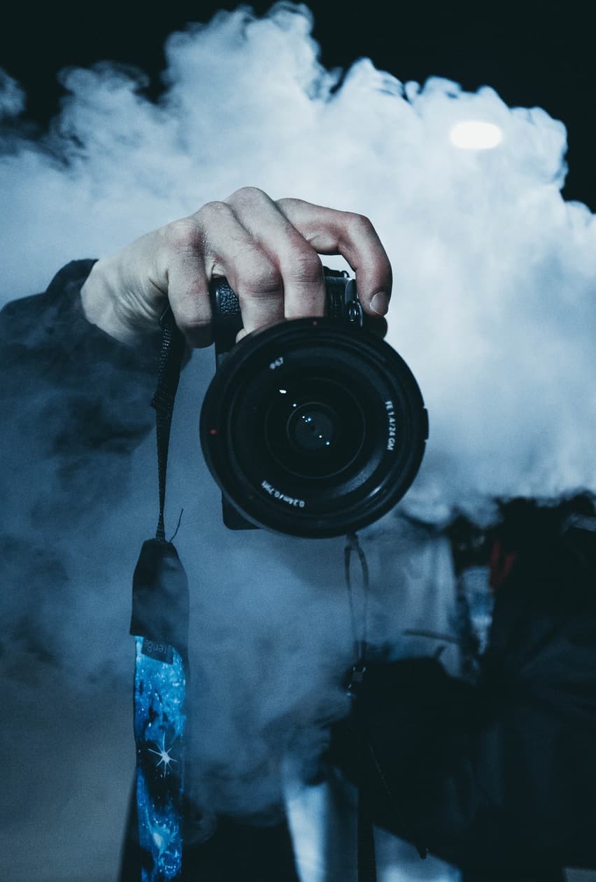 Фотоаппарат в руке сквозь облако дыма